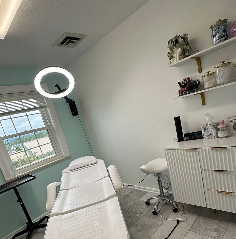 The treatment room with a treatment bed, ring light and supply cart